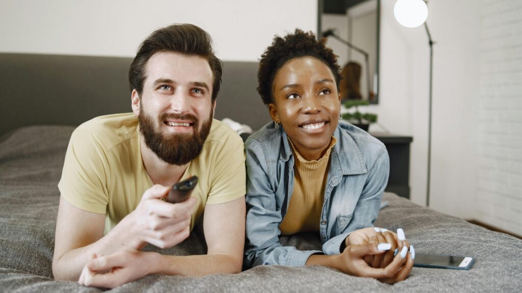Casal assistindo televisão juntos em uma sala de estar aconchegante em casa.